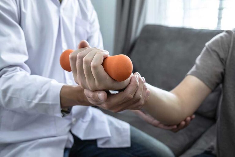 Physical therapist guiding a patient through a gentle movement assessment in a bright treatment room.